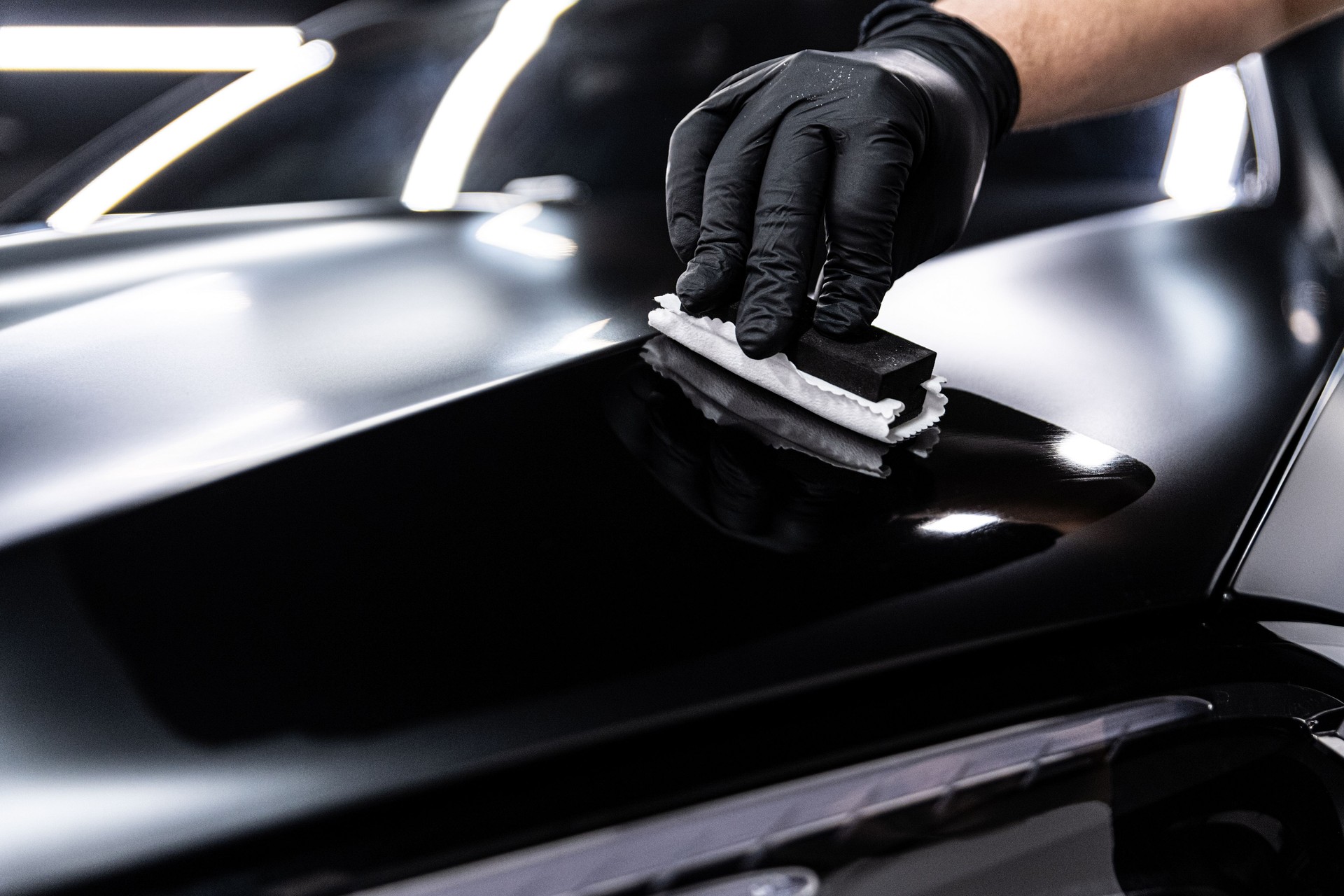 Car wash or detailing studio employee applies ceramic or graphene coating